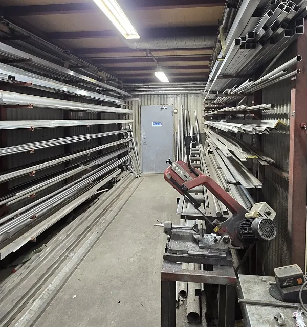 Verkstedhall med metallhyller fylt med metallprofiler og stenger